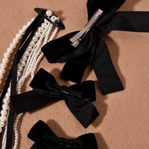 Detail of elegant black velvet and satin bow hair clips with silver crocodile clip backings