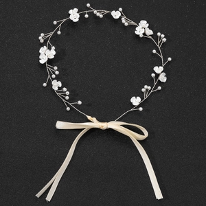 Détail du bandeau de mariée avec perles blanches et fleurs en céramique sur fond noir