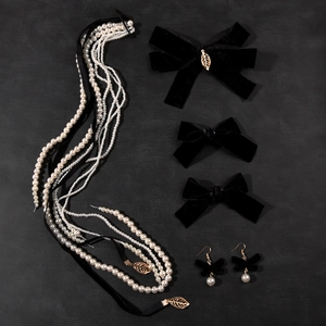 Detailed set of black velvet bow hair clips with pearls and gold leaf necklace