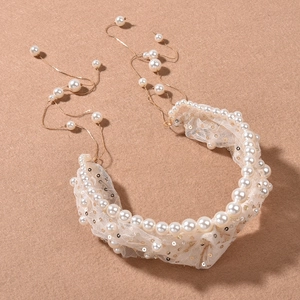 Detail of bridal headband featuring white pearls, lace base, and golden sequins