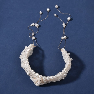 Detail of bridal headband with white pearls and sequins on elegant mesh fabric with gold chains