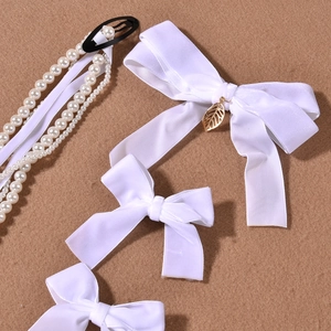 Detail of white velvet bow hair clips with pearls and golden leaf tassels for women