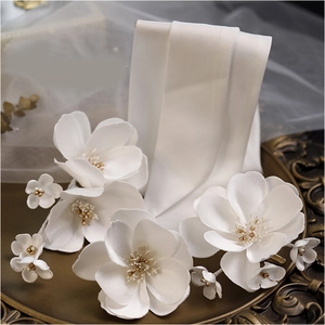 Accessoires de mariée en satin blanc avec perles dorées sur un plateau en bronze