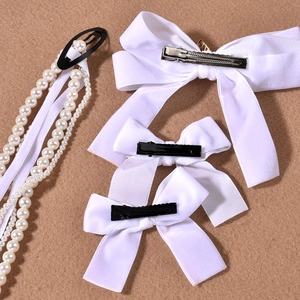 Detail of white satin bow hair clips with elegant artificial pearl fringe and metal clasp