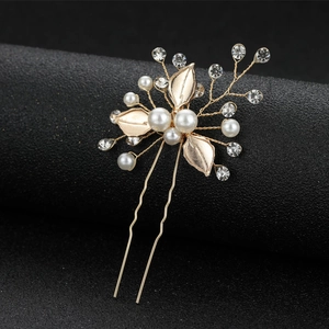 Elegant gold bridal hair pin with white leaves, faux pearls and crystals on a black stand