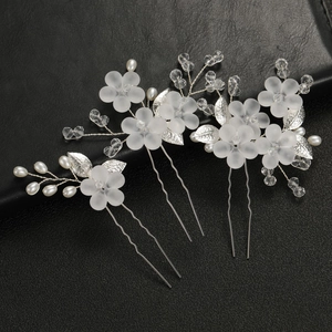 Detailopname van bruidshaarspelden met matte witte bloemen, parels en kristallen kralen