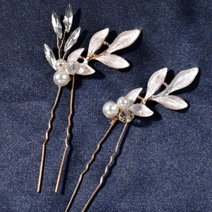 Detail of golden alloy hairpins with white enamel leaves and clear crystals on denim