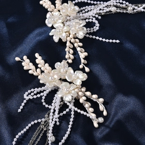 Détail de pince à cheveux de mariée avec perles blanches et pompons argentés sur satin