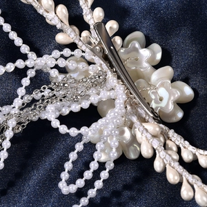 Détail d'une pince à cheveux de mariée vintage avec fleurs perlées et glands argentés