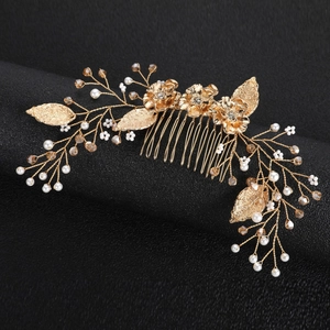 Golden bridal hair comb with handmade crystal leaves and pearls on a black display stand