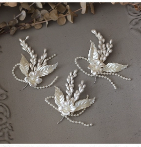 Three-piece bridal hair accessories set with white flowers and pearls on gray background