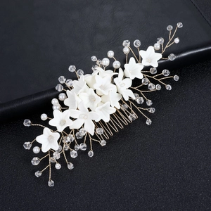 Elegant bridal hair comb with white flowers, pearls and crystals on a golden metal base