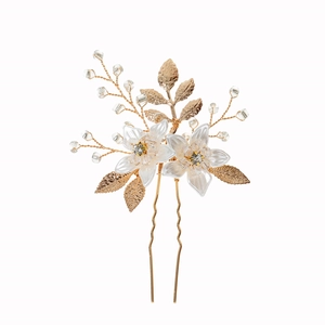 Close-up of handmade bridal hair pin with white resin flowers and gold leaf details