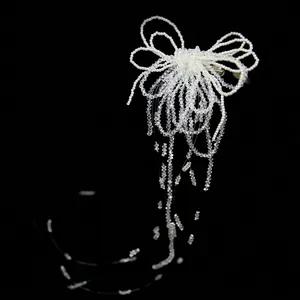 Pince à cheveux de mariée avec perles blanches et longs glands en cristal sur fond noir profond
