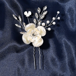 Dettaglio forcina sposa con fiore perlato, cristalli e perle su sfondo di seta blu scuro
