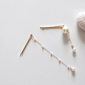 Détail de barrettes dorées avec glands en perles et design minimaliste en alliage
