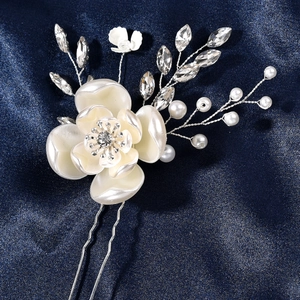 Vista macro di forcina per capelli sposa con fiori bianchi e perle su seta blu