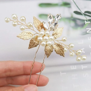 Detailed macro view of golden metal leaves and white pearls on the bridal hair pin
