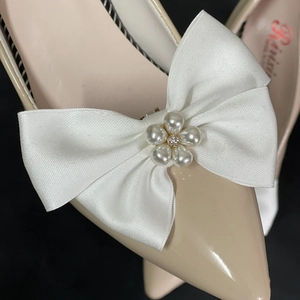 Détail d'un nœud en satin blanc avec fleur de perles et cristaux sur chaussures vernies