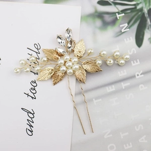 Macro detail of handmade golden leaf hair pin with white pearls and sparkling crystals