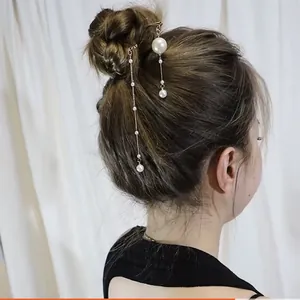 Détail de pinces à cheveux élégantes avec perles et pompons sur une coiffure relevée