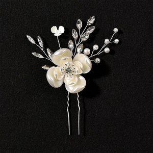 Dettaglio macro della forcina per capelli con fiori bianchi da sposa e cristalli su sfondo nero