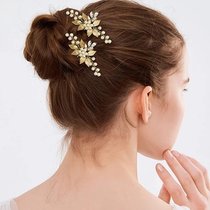 Detailed view of two gold leaf hair pins with pearls and rhinestones on a bridal updo