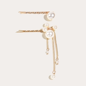 Détail de deux barrettes à cheveux dorées avec perles et chaînes à pampilles