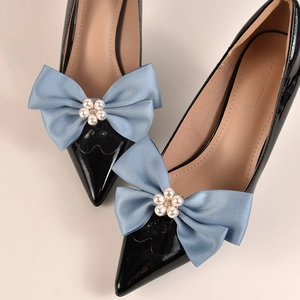 Macro d'un nœud en satin bleu clair avec perles et strass sur des talons noirs
