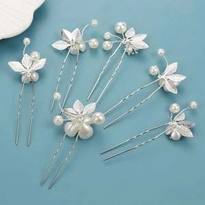Detailed close-up of six silver clover hair pins with pearls on a blue background