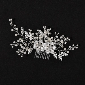 Détail d'un peigne de mariée avec fleurs en métal argenté, strass et perles blanches