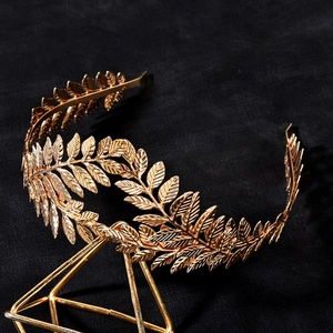 Baroque golden leaf headband crown hair accessory displayed on a geometric metal stand