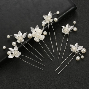 Detailed view of six silver U-shaped hairpins with white flowers and pearls for brides