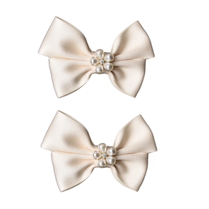 Détail de clips de chaussures de mariée avec nœuds satinés et perles blanc crème