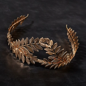 Detailed top view of a gold leaf laurel crown headpiece on a black fabric background