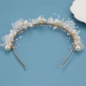 Détail de pétales de fleurs blanches et perles faites main sur un bandeau de mariée doré