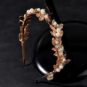 Detailed macro view of golden metal leaves and white pearls on the bridal headband