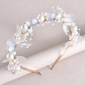 Détail de serre-tête de mariée avec fleurs en résine blanche et perles sur cadre doré