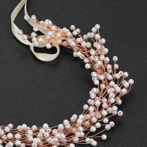 Braut-Haarschmuck mit weißen Perlen und Roségolddraht auf schwarzem Hintergrund