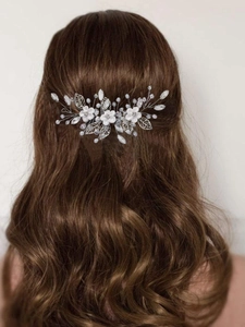 Close-up of bridal hair comb with white flowers and silver leaves on brown hair