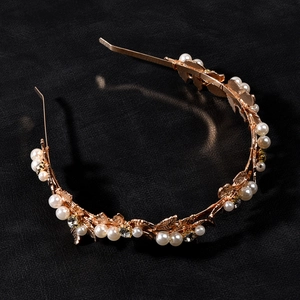 Detailed close-up of rose gold leaf headband with white pearls and sparkling rhinestones