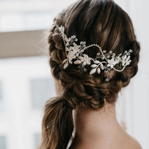 Silver bridal hair vine with white flowers and crystals worn on a braided wedding hairstyle