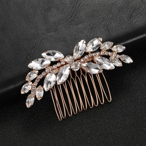 Macro detail of rose gold bridal hair comb with emerald and crystal leaf design