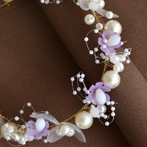 Détail macro du bandeau fait main avec fleurs blanches, violettes et perles dorées