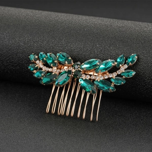 Macro detail of gold bridal hair comb with emerald green stones and white crystals