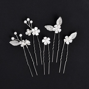 Détail d'épingles à cheveux de mariée avec fleurs blanches et perles sur sable noir