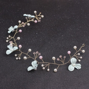 Detail der Braut-Haarranke mit grünen Blumen, Perlen und goldenem Draht auf dunklem Grund