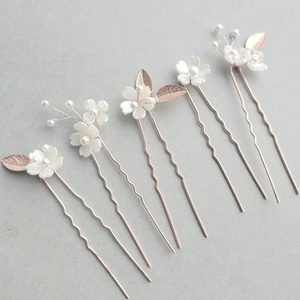 Détail de cinq épingles à cheveux de mariée blanches avec perles et feuilles d'or rose