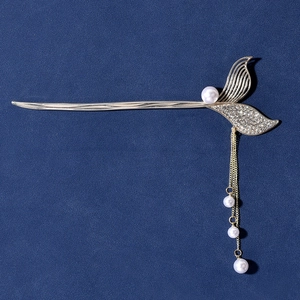 Elegant gold mermaid tail hair pin with white pearls and tassels on dark background