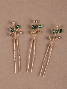Détail de trois épingles à cheveux de mariée dorées en U avec strass verts et clairs